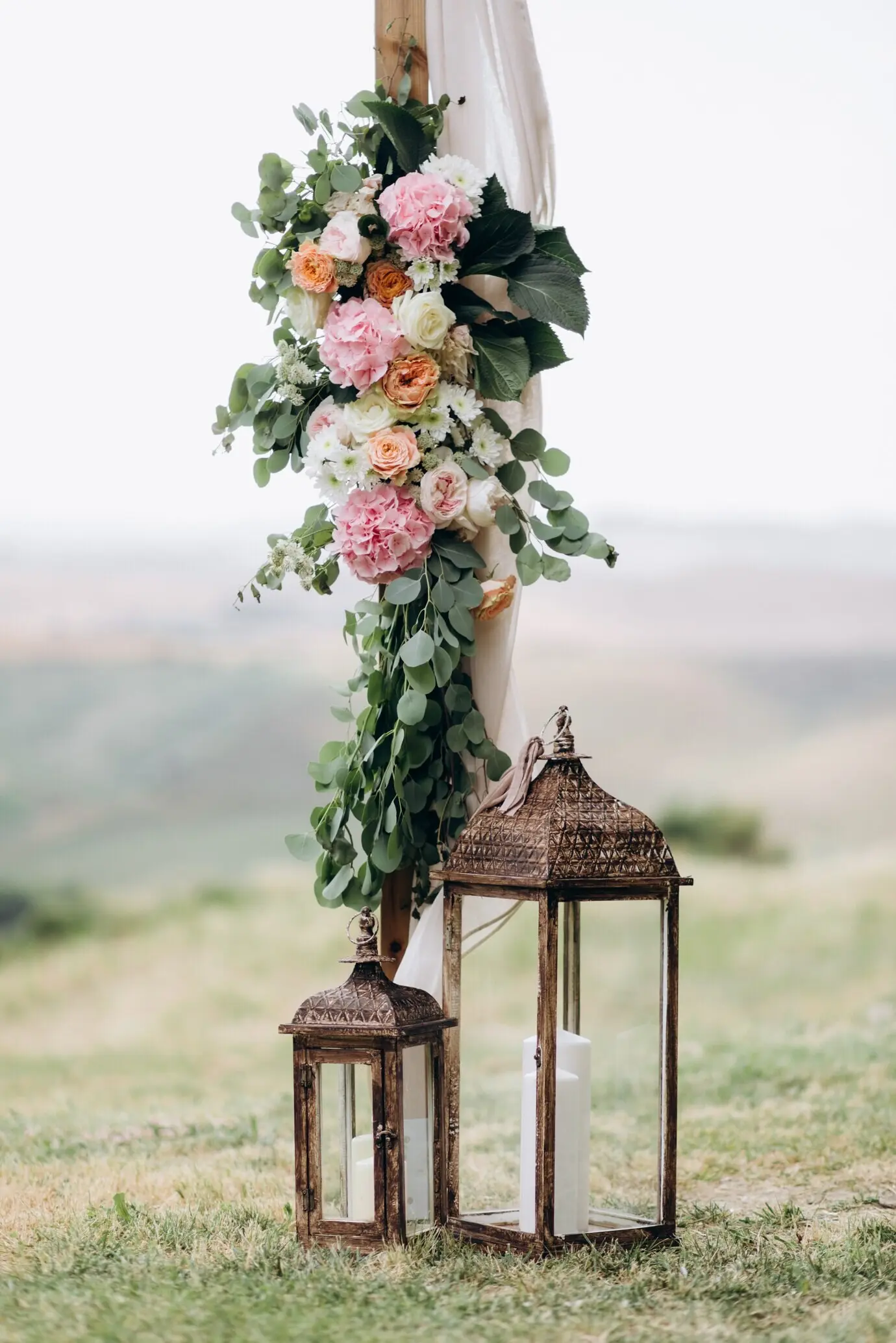 Флористическая композиция из эвкалипта и нежных розовых цветов со свечами на открытом воздухе.